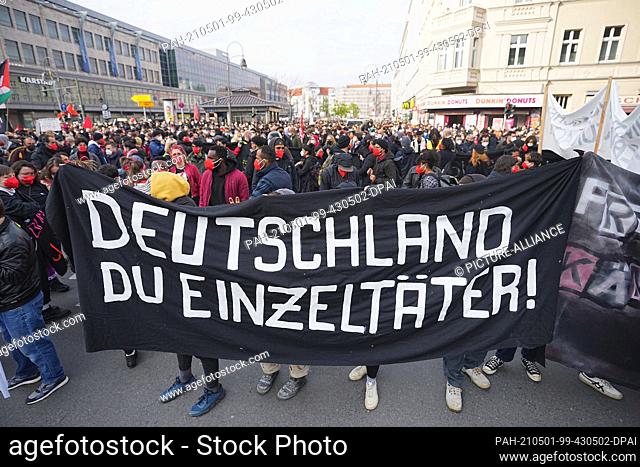 01 May 2021, Berlin: ""Germany you lone perpetrator!"" is written on the banner held by participants in the demonstration march of left-wing and radical...