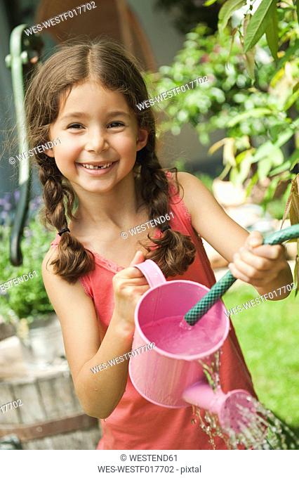 Germany, Bavaria, Girl gardening with watering can, smiling, portrait