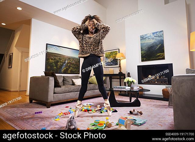 Female ballet dancer among sea of toys in a living room