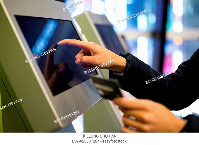 Woman using credit card to pay on the automatic cinema ticketing terminal
