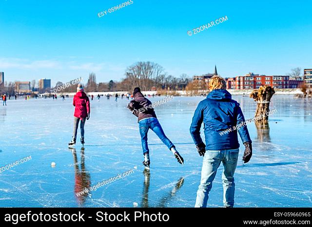Wagenignen, The Netherlands - February 13, 2021: Ice skaters having fun in the sun on frozen floodplains along river Rhine in Holland
