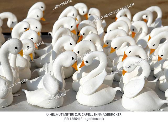 Meringue swans with beaks made from apricots in a patisserie