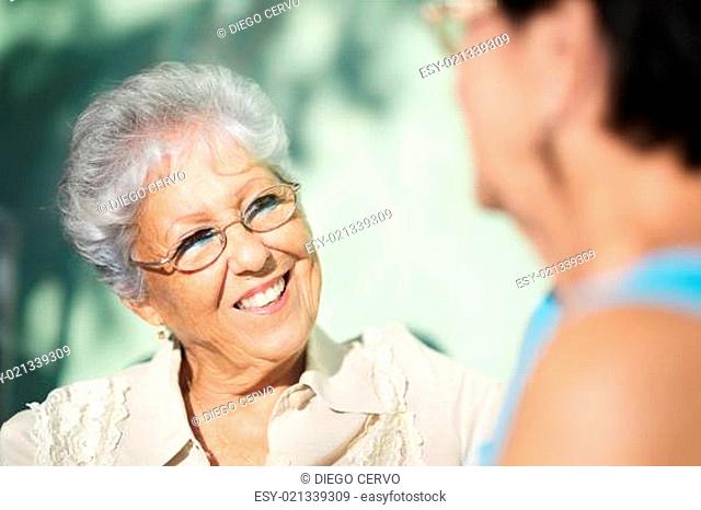 Old friends, two happy senior women talking in park