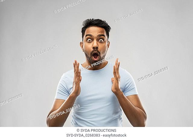 scared man in t-shirt over grey background