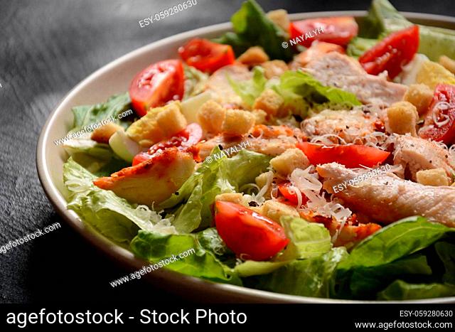Caesar Salad with grilled chicken, Cheese and Croutons with lettuce, on plate. Grilled chicken breasts and fresh vegetables in plate