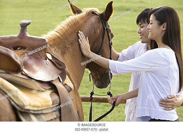 Couple stroking horse