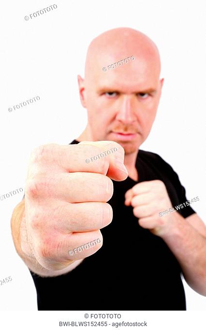 bald headed, young mean man threatening with his fist