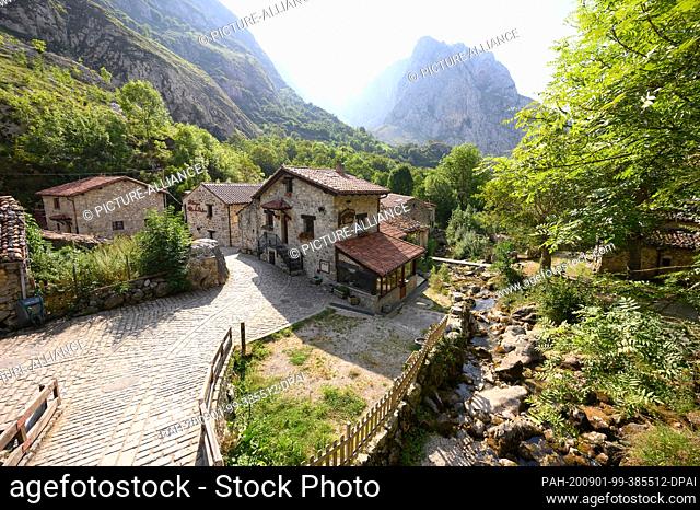 07 August 2020, Spain, Bulnes: The river Rio Bulnes flows in front of the limestone cliffs in the National Park Picos de Europa through the village centre