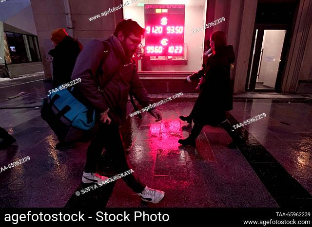 RUSSIA, MOSCOW - DECEMBER 21, 2023: People walk past an information board showing foreign currency exchange rates. The Bank of Russia has set the US dollar rate...