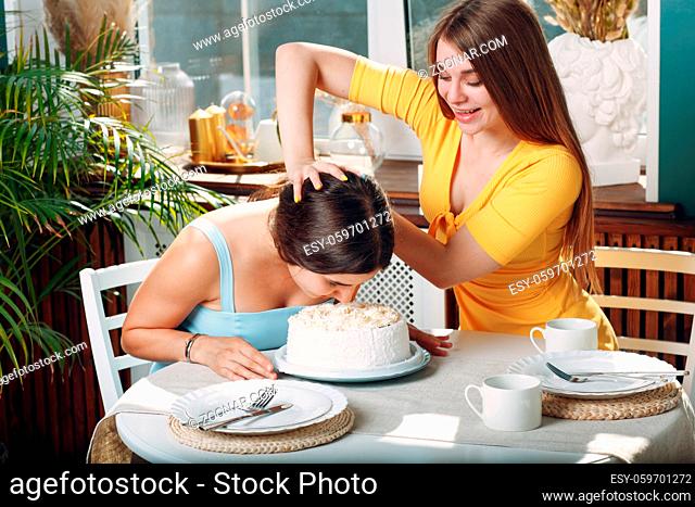 Young woman dips face in white cake with cream. Happy birthday concept
