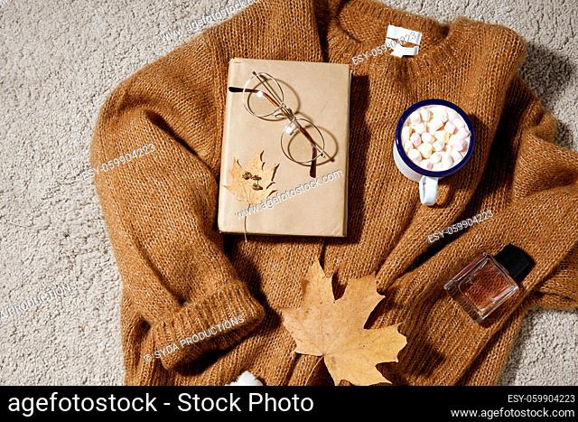 cup of marshmallow, book and glasses on sweater