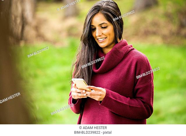 Smiling Indian woman texting on cell phone