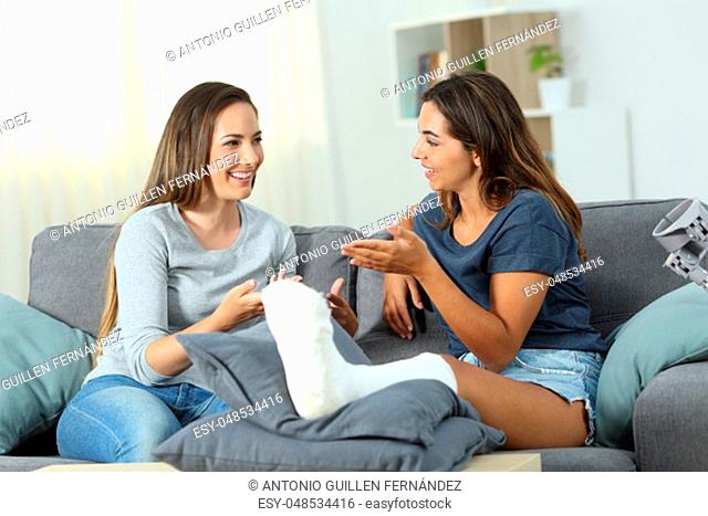 Disabled woman talking with a friend sitting on a couch in the living room at home