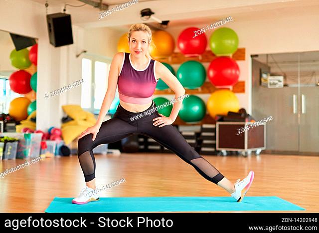 Junge Frau macht eine Stretching Übung für die Beine auf der Yogamatte