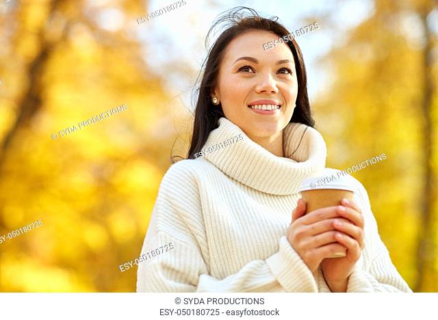 woman drinking takeaway coffee in autumn park