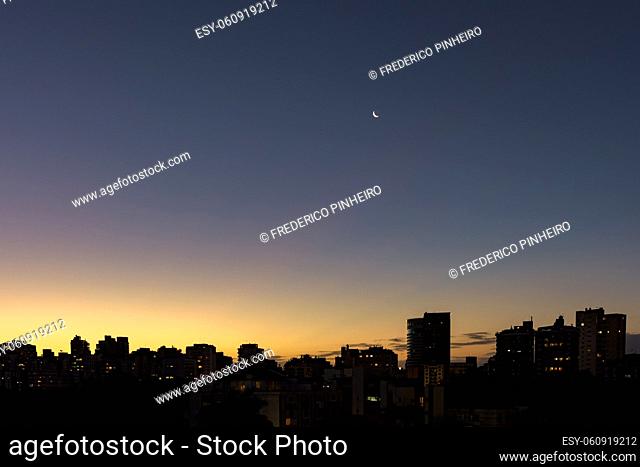 Skyline of Porto Alegre at dusk with the moon in the sky with buildings silhuette