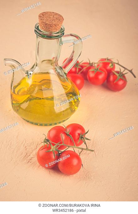Ingredients for Italian cuisine - a bottle of vegetable oil and cherry tomatoes on a light background. Toned Photo