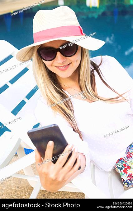 The attractive blond hair woman in hat and sunglasses is using phone