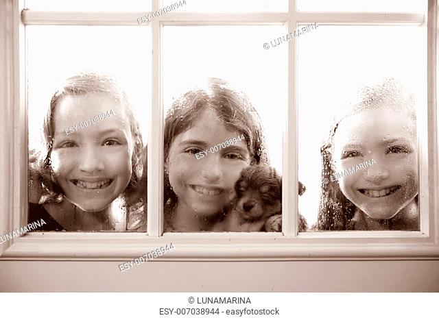 three sister friends looking through the window with a pup and raindrops