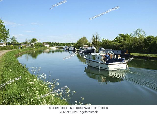 A small boat cruises towards the swing bridge at Purton Gloucester & Sharpness Canal at Purton in summer sunshine, Gloucestershire, UK
