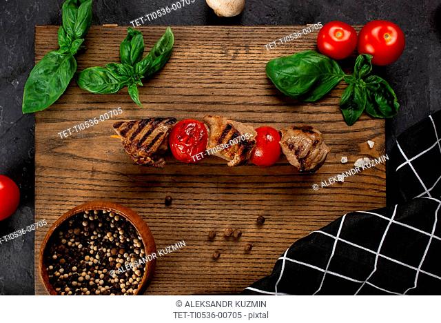 Grilled meat and tomato skewer on cutting board