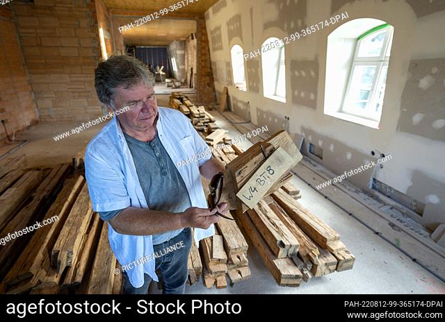 12 August 2022, Saxony, Plauen: Harald Haupt, specialist advisor for construction at Plauen City Hall, shows wooden beams from the 18th century at the...