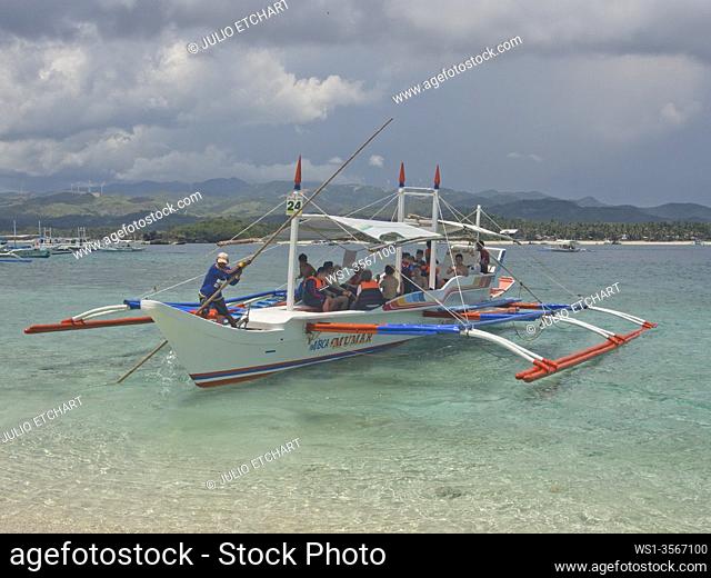 Tourists boarding a traditional panga boat in Boracay, Philippines