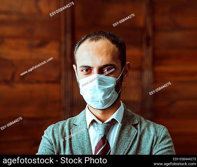 Well-Dressed Man In Protective Mask Looks At Camera, White Collar Male Worker Or Boss Standing In Deserted Office Alone During Quarantine Due To Epidemic Of...