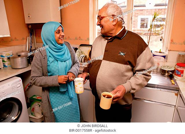 Asian carer with elderly Asian man in the kitchen chatting and making tea, ***NOT TO BE USED IN THE EAST MIDLANDS***
