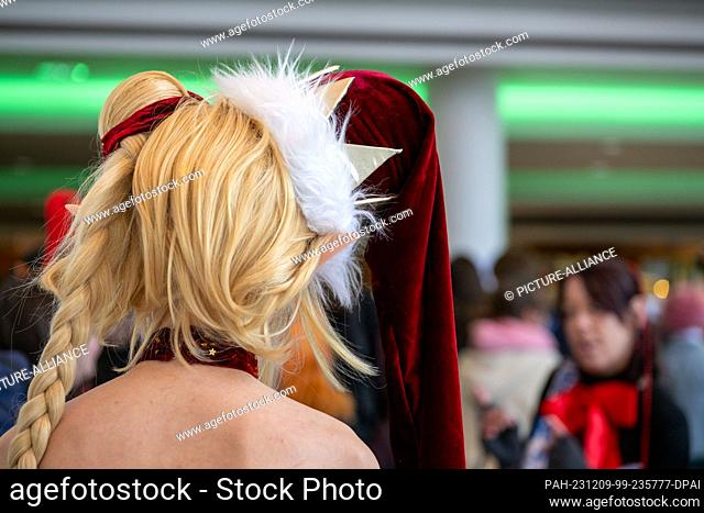 09 December 2023, Bavaria, Coburg: A woman with a wig and a Christmas crown on her head waits in the midst of numerous other costumed people