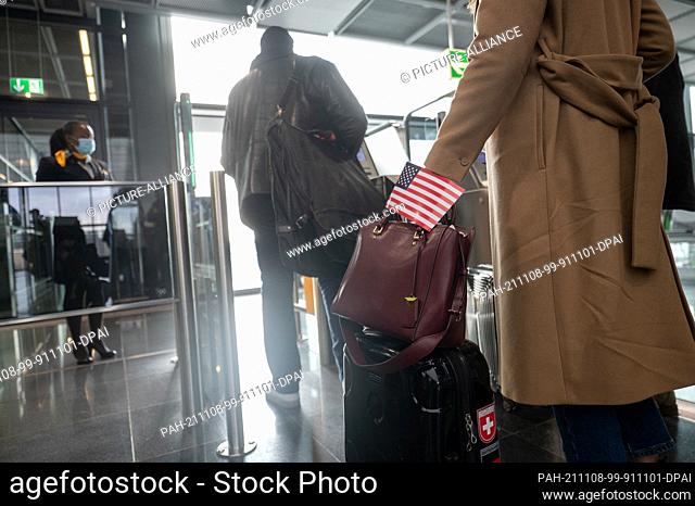 08 November 2021, Hessen, Frankfurt/Main: A woman walks through the boarding area at Frankfurt airport with a USA flag for a Lufthansa flight to New York