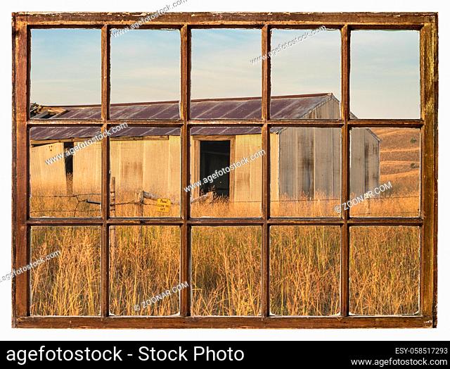 old metal barn in Nebraska Sandhills as seen from a vintage sash window