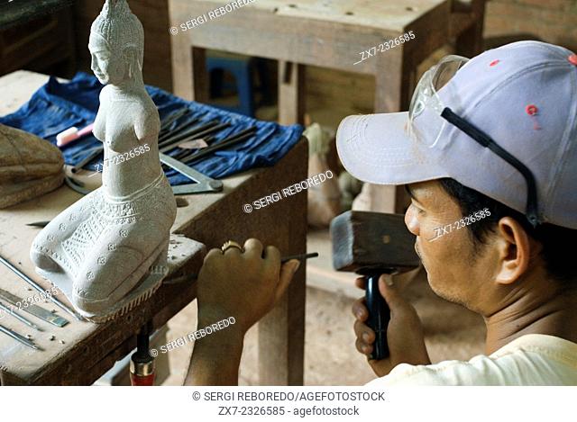 Sculptor at work at Artisans d'Angkor, Siem Reap, Cambodia. Young Cambodian artisan during the artistic craftsmanship of stone with a wooden hammer and a chisel...