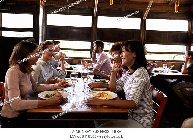 Four female friends at a girls’ lunch in a busy restaurant