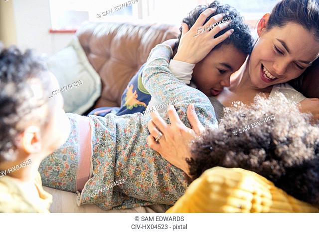 Affectionate mother and children cuddling on sofa