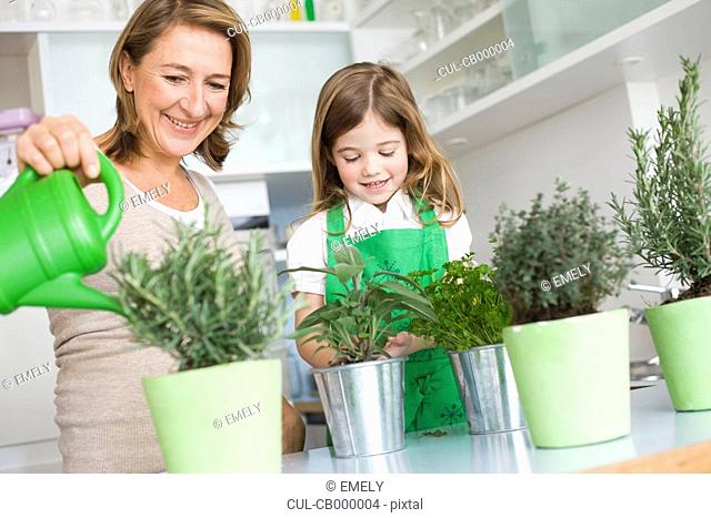 Daughter and mother watering herbs