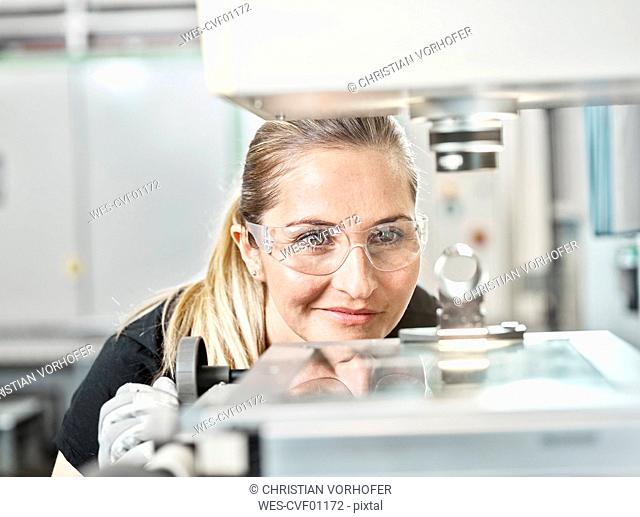Woman working on a machine, looking on spring