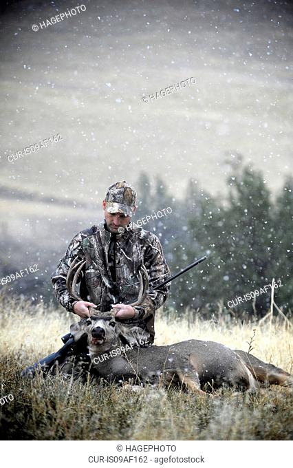Deer hunter holding up dead stags antlers, John Day, Oregon, USA