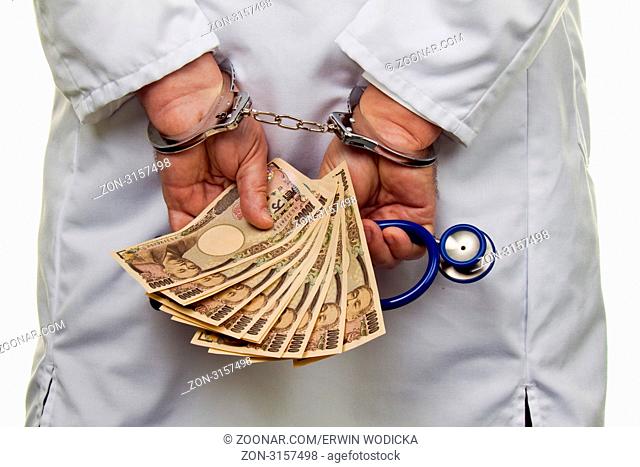 Ein Arzt mit japanischen YEN Geldscheinen und Handschellen