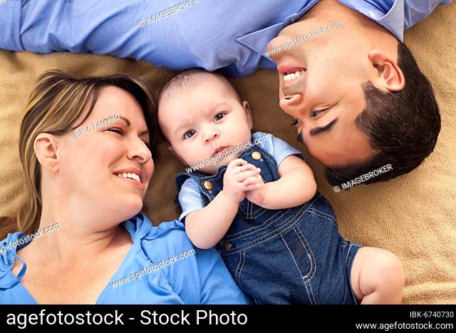 mixed-race family playing face up on the blanket