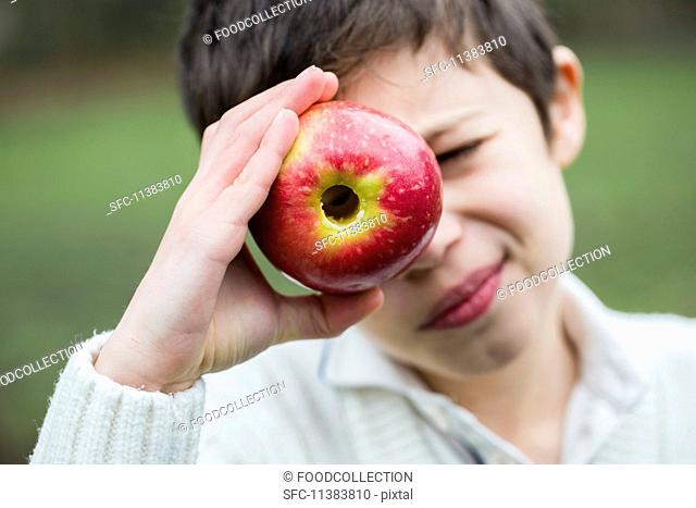 A little boy looking through a cored apple