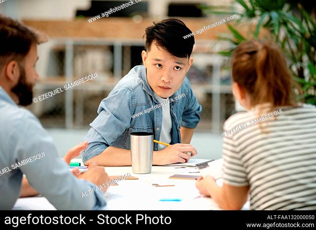Young adult architect listening carefully to colleague