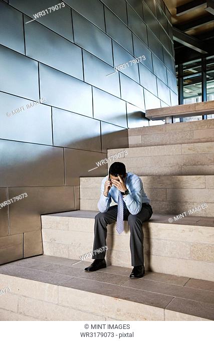 Businessman in a stressful situation while on a cell phone in the lobby of a large office building