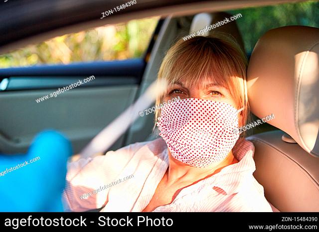Seniorin mit Mundschutz in ihrem Auto fährt in Drive-In für Schnelltest vor während der Coronavirus-Pandemie