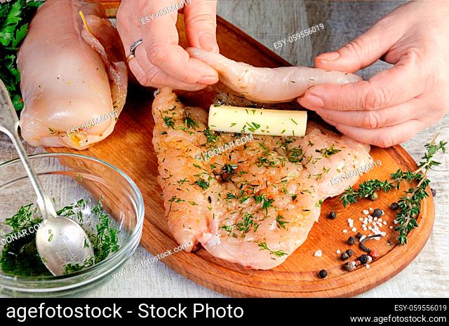 Cooking. A woman's hand, wraps a piece of mozzarella in a chicken breast greased with a dressing with dill. Step-by-step recipe