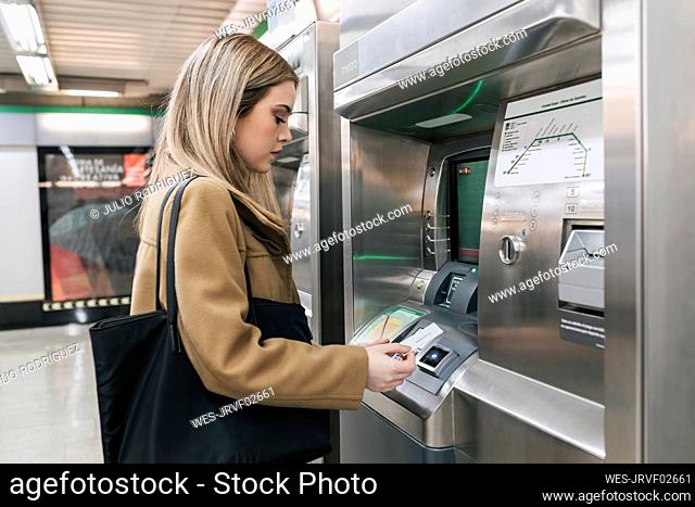 Woman with purse paying with credit card and buying ticket at station