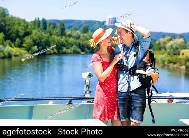 Happy couple on river cruise wearing sun hats in summer