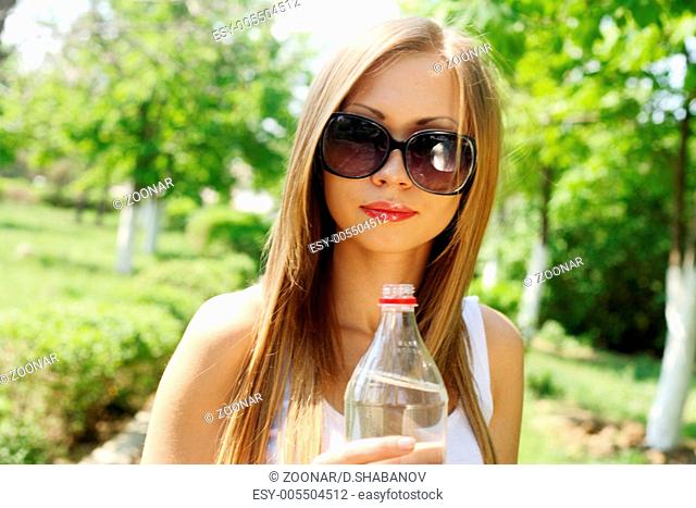 beautiful woman drinking water at summer green park