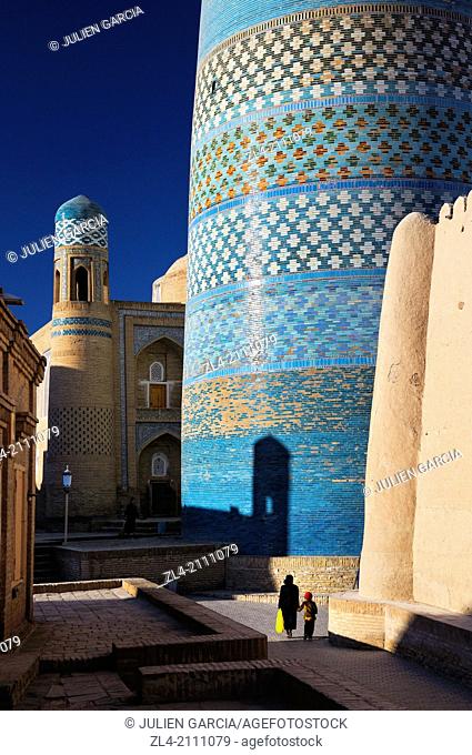 Woman and her son walking by the unfinished minaret Kalta Minor. Uzbekistan, Khorezm, Khiva, Itchan Kala (inner town)