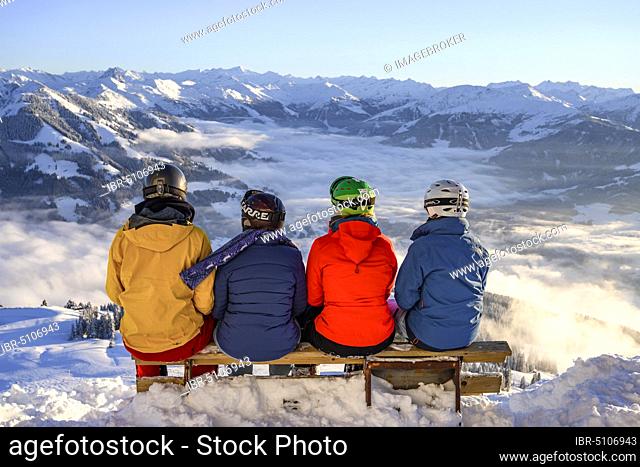 Skiers sitting on a bench and looking down on snow-covered mountains, SkiWelt Wilder Kaiser Brixental ski area, Brixen im Thale, Tyrol, Austria, Europe